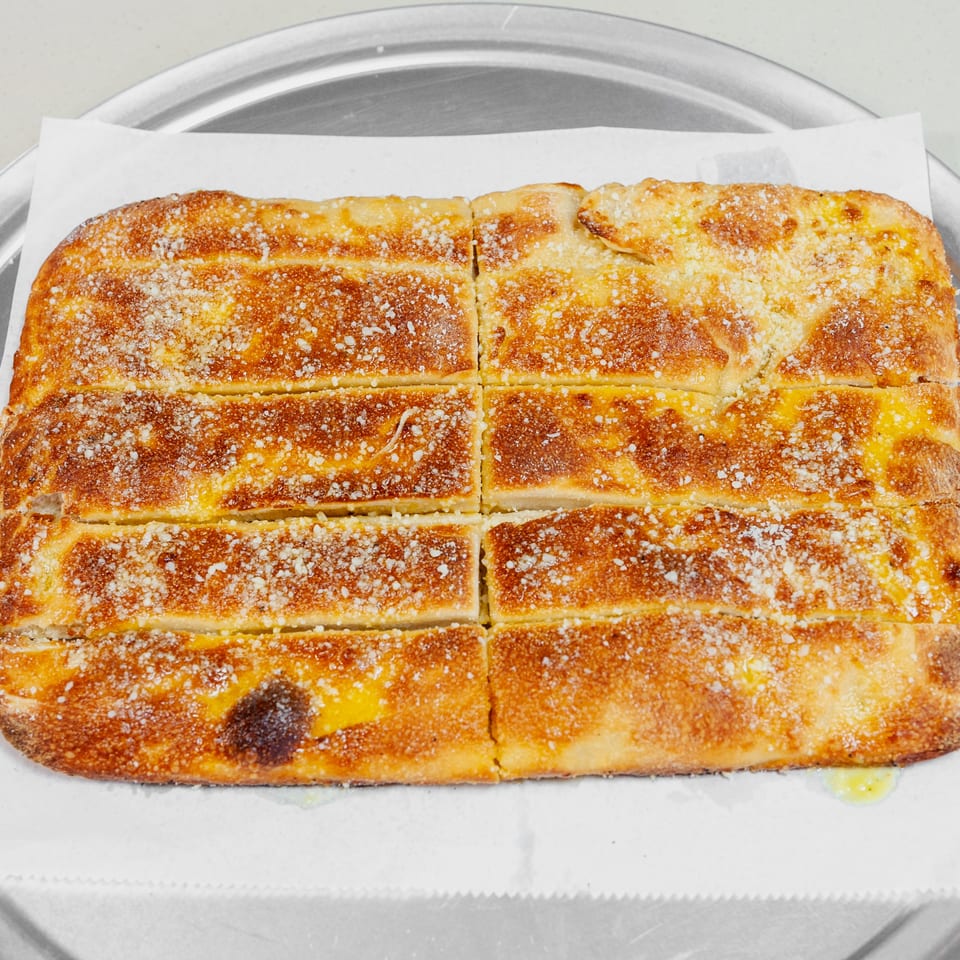 Golden-brown rectangular baked pastry cut into eight pieces, sprinkled with sugar, and served on parchment over a metal tray.