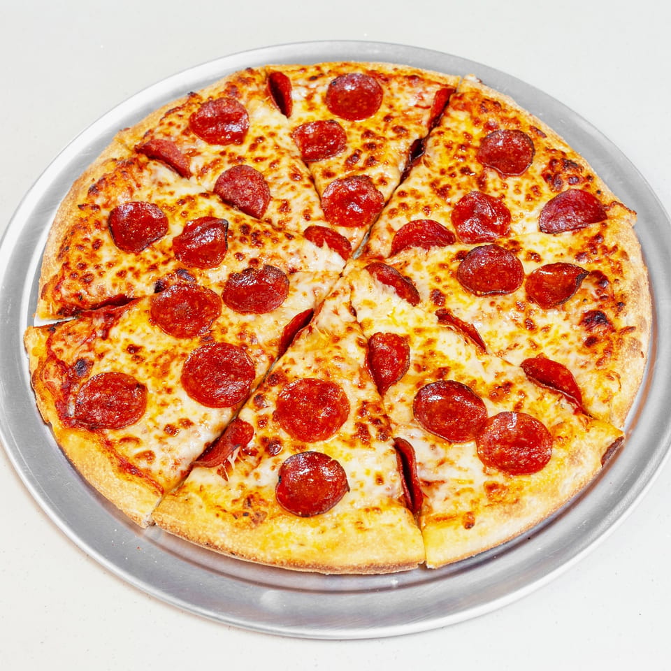 Round pepperoni pizza sliced into wedges on a metal serving tray.